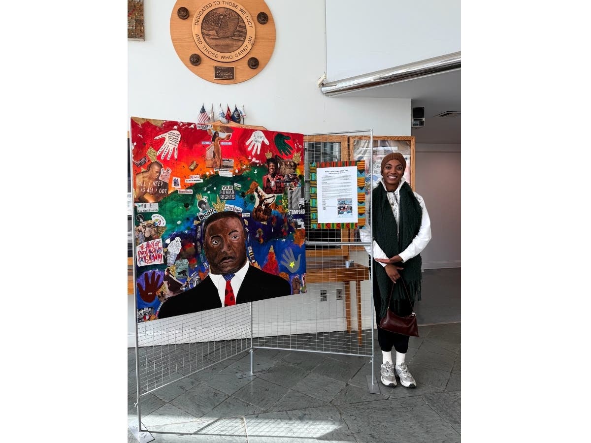 Local artist Sahmra Sawyer stands with the community canvas, "Martin Luther King Jr. (1929-1968)”, on display at the Stamford Government Center in celebration of Black History Month.