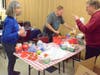 Aurora Noon Lions Sue Koepke (left) Bill Poss and Dick Schindel pack gift buckets to be distributed at their 15th annual pizza party for deaf and hearing-impaired kids Thursday.