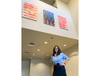 Art teacher Lindsey Brown stands below her artwork in the Plainfield Police Department's Branch Court lobby.