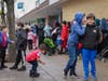 Families wait in line outside the local ICNA Relief food pantry to receive food and other services.
