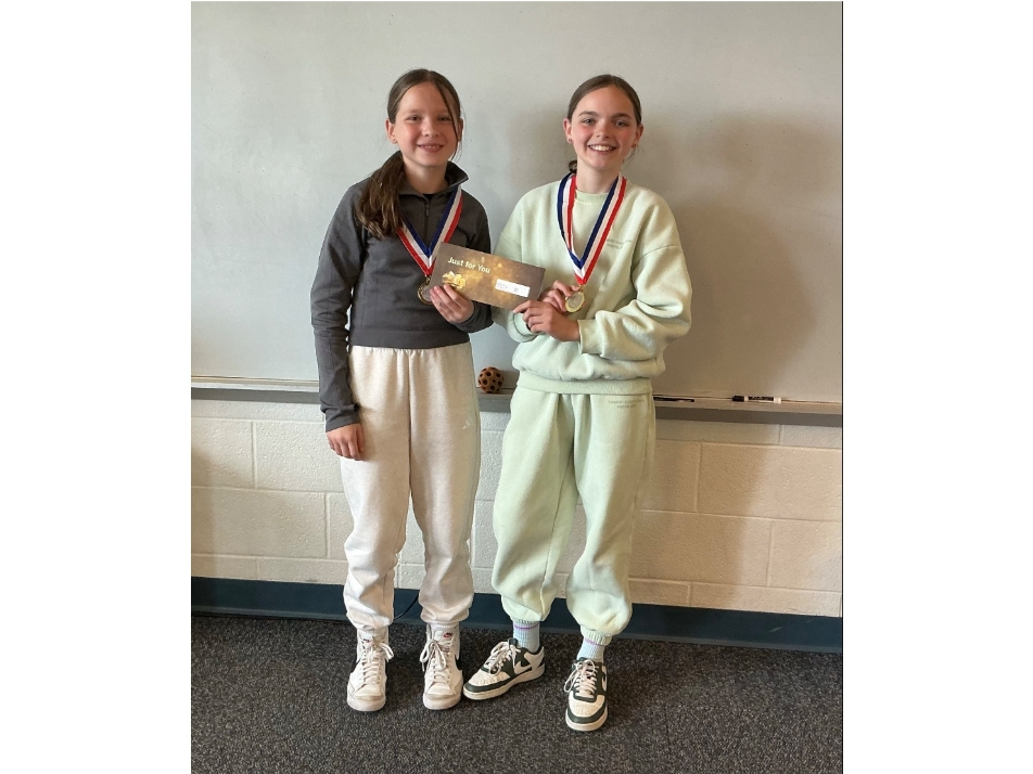 Lucy and Nora show off their medals and prize money from taking second place in the Stock Market Game.