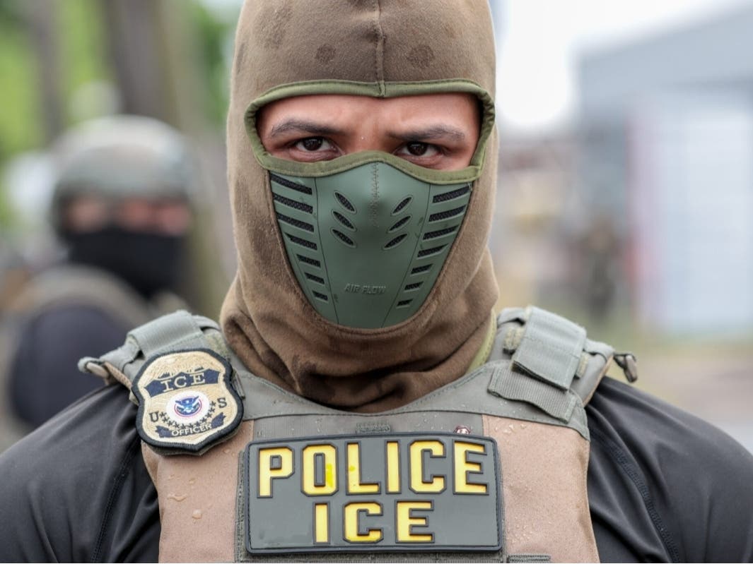 A U.S. Immigration and Customs Enforcement agent watches a crowd of protesters at Delaney Hall in Newark on May 25, 2026. 