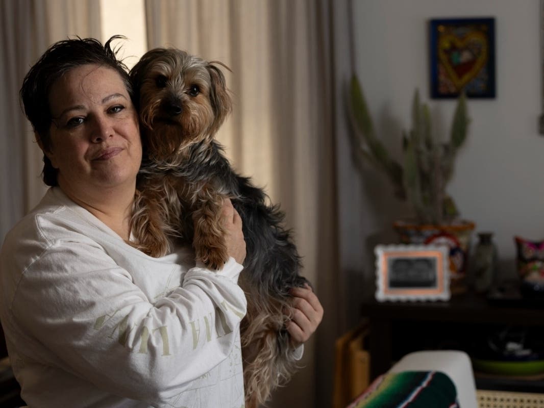 Julie Moreno, a volunteer with American Families United, with her dog Topo Chico in her Newark home on April 9, 2026. Moreno’s husband, Nef Juarez, self-deported to Mexico last year in October