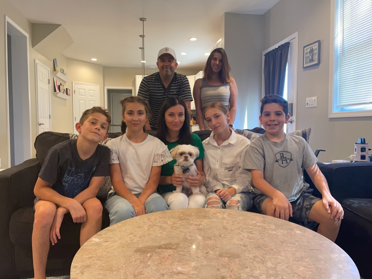 The seven combined family members in Bridgewater pose for a photo. Front row: Owen Bitner, Sofiia, Liza (holding Luke Skybarker), and Yeva Burlaka, and Ben Bitner. Back row: Justin and Christy Bitner. Alexander Burlaka is still in Ukraine. 