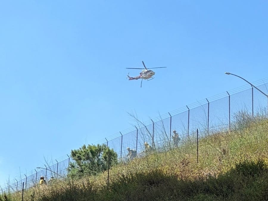 A brush fire erupted Monday on a hillside near a boundary separating Orange and Riverside counties, quickly burning through three acres and slowing traffic for miles, authorities reported.