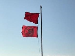 A single red flag recommends swimmers stay out of the water, the new double red flag requires swimmers to stay out of the water, officials said.