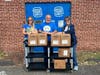 Enfield Food Shelf Director Kathleen Souvigney accepts meal packets from Rotary Club of Enfield President Aimee Nieroda and Board Member Joe Muller. 