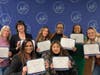 Eight members of the January 2023 Inclusive Ventures Program cohort with certificates of completion that they received, along with $5,000 operating grant checks, at the Anne Arundel Economic Development Corporation's office on March 3, 2023.