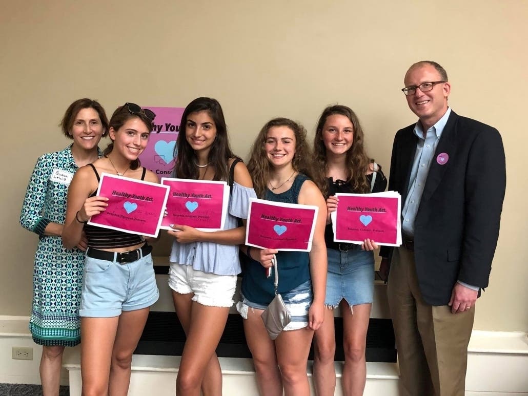 Senator Jason Lewis (right) joined his wife, Susan, and daughter, Jessie (left) with other youth advocates at a 2018 State House rally in support of the Healthy Youth Act.