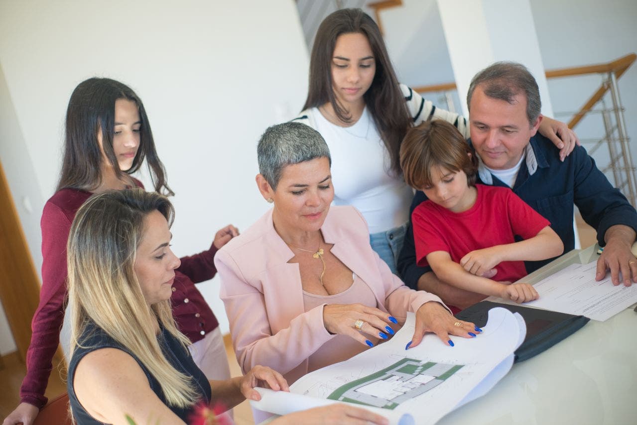 A family focused on purchasing a new home discusses property plans with a realtor
