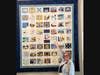 Kathy Schreiber points to the America 250! Quilt with the NY Quilt square submitted by the Polly Cooper Chapter