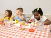Children sharing peanut butter and snacks at a dining table. 