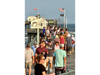Crowds walk to and from the the end of the nearly 750-foot long Ocean City Fishing Club pier that extends from the Boardwalk, over the beach and the Atlantic Ocean.