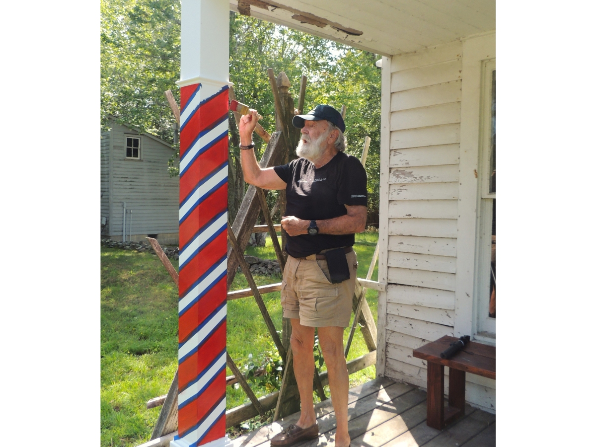 Historian Curt Watts paints the porch posts. The blue lines are painter's tape.