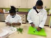 Kennedy School students chop fresh parsley from the school garden and prepare to add it to a dish in cooking class.