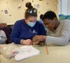 St. Coletta’s of Illinois Recreational Therapist Stephanie Wingo helps a participant make a bracelet from beads, improving her fine motor skills and manual dexterity.