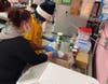 Kennedy School culinary arts teacher Belen Hernandez helps a student measure sugar for a batch of cupcakes ordered by Atlas Putty Products Co. 