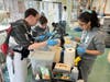 Jose (left) shows classmates how to fill the food dishes at NAWS Humane Society in Mokena while a kitten looks over his shoulder, waiting to be fed.