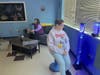 Sue K. watches plastic fish dance inside a bubble tube while Jennifer B. relaxes on a nearby couch.