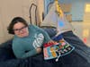 Alyssa A. flips through a fidget book while relaxing on a crash pad inside St. Coletta’s new sensory room.