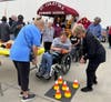 A volunteer from All Saints Lutheran Church in Orland Park assists an adult participant with the ring toss game, spreading joy and excitement at St. Coletta's annual Fall Fest.