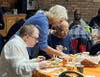 An All Saints Lutheran Church volunteer shares a warm moment with one of St. Coletta’s adult participants, helping him butter a dinner roll at the Thanksgiving feast on Nov. 20. 