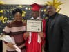 Graduate Keith shares a proud moment with his mom and dad as they pose together for a photo on his special day at Kennedy School.