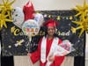 Proud graduate Brianna poses with a big smile after the ceremony, holding balloons and flowers lovingly gifted by her parents.