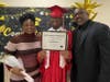Graduate Keith shares a proud moment with his mom and dad as they pose together for a photo on his special day at Kennedy School.