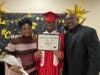 Graduate Keith shares a proud moment with his mom and dad as they pose together for a photo on his special day at Kennedy School.