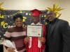 Graduate Keith shares a proud moment with his mom and dad as they pose together for a photo on his special day at Kennedy School.