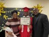 Graduate Keith shares a proud moment with his mom and dad as they pose together for a photo on his special day at Kennedy School.