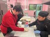 Bakery Manager Elsa Espinosa Diaz guides Mary as she prepares to roll out cookie dough during the first hands-on baking session at Coletta’s Crossing Bakery.