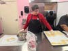 Mary carefully places the heart-shaped dough onto the cookie sheet.