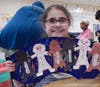 Smiling with pride, a student holds up her finished Black history Month artwork celebrating diversity, friendship and the message that all skin is beautiful.