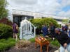 A St. Coletta’s staff member places a flower in the basket beneath the Blessed Mother statue as Kennedy School student Najee and Community Day Services participant Cole, assisted by CEO Heather Benedick, approach to crown the statue with flowers.