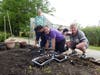 Clinical Therapist David Saavedra helps participants, Matthew, David and Amy plant vegetable seeds near the reopened greenhouse. Amy proudly shows off a packet of beet seeds as the group gets ready for another growing season.