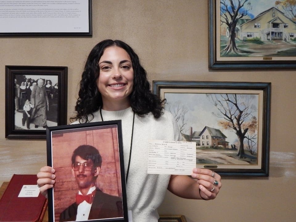 Meghan Martewicz, a clinical therapist at St. Coletta's of Illinois, stands with a photograph of her late uncle, Brian, and his original Kennedy School registration card after discovering that he attended the organization more than 50 years ago. 