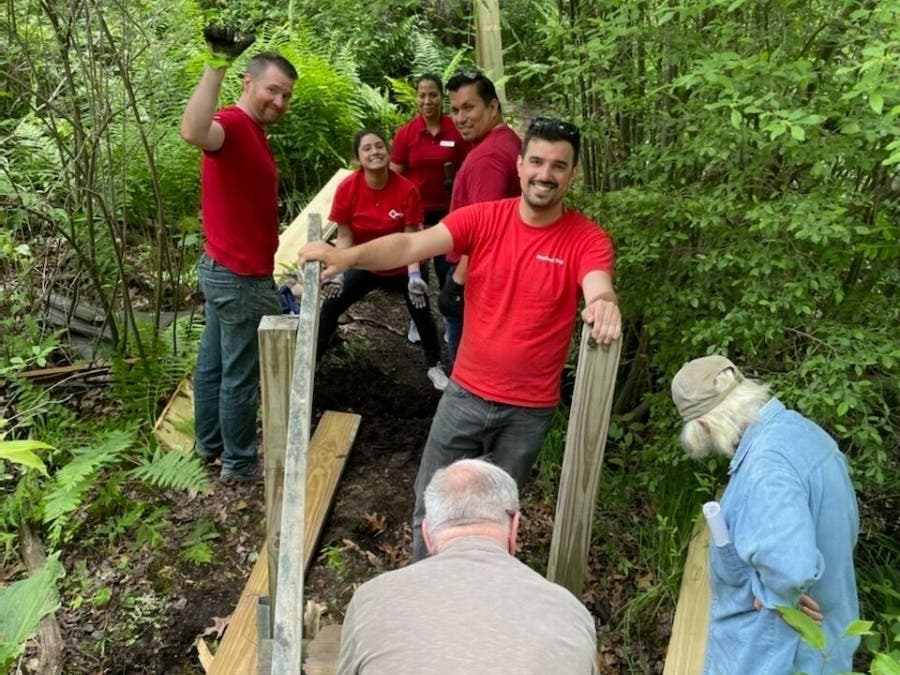Volunteers with KeyBank get to work Tuesday on fixing up the Hockanum River Trail network in Ellington.