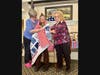 Quilts of Valor Foundation Volunteer, Cindy Guendert, left, and Middlewoods of Farmington Activities Director Debbie Astrom, right, help 'wrap' veteran Leomonia 'Lee' Pappas with her newly awarded Quilt of Valor.