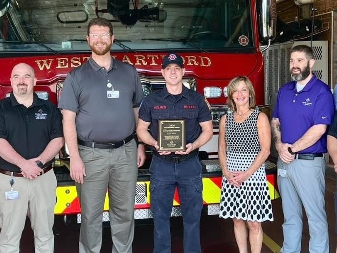 West Hartford firefighter paramedic David Holmes, holding a plaque, has been named a recipient of Saint Francis Hospital’s 2026 EMS Champion Award.