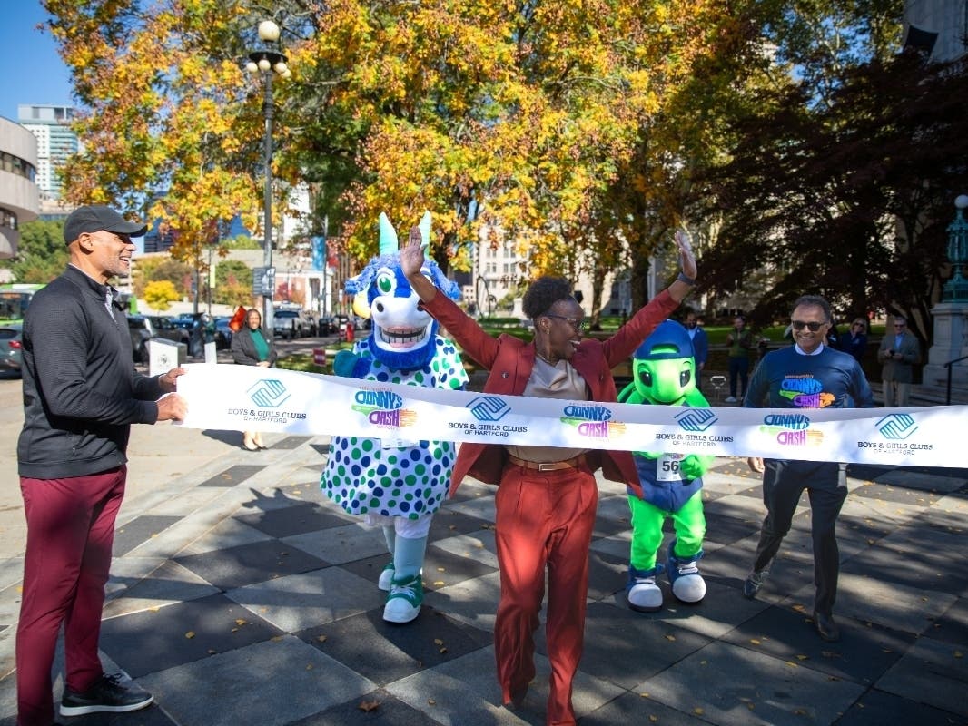 Hartford Mayor Arunan Arulampalam hosted a 'Mascot Marathon' at City Hall this week to promote 'Donny's Dash.' Above, Alise Dixon, head of Boys & Girls Clubs of Hartford, won. Holding the ribbon on the left is UConn basketball legend, Donny Marshall.
