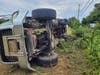 The overturned truck came to rest in a field next to the roadway.