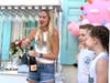 Lindsay Baker celebrates the opening of Mom's Cookie Bar with a bottle of champagne as two of her children look on.