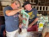 Frank Brassell and Mayor John Burke pour sand into a bag.