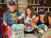 Judy Musto, center, helps Mayor John Burke and his wife, Marybeth, assemble luminary kits.