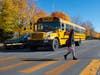 A car is stopped behind the extended bus arm.