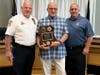 Chief John Hearn and Lt. Jason Harris present a retirement plaque to Officer Ferraro.