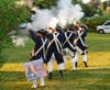 Firing a musket salute are Revolutionary War reenactors from Crossing Community Church.