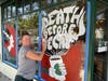 Shannon Stucky works on her "Death Before Decaf" painting on the windows of Starbucks. That's the Bride of Frankenstein holding the cup of decaf.